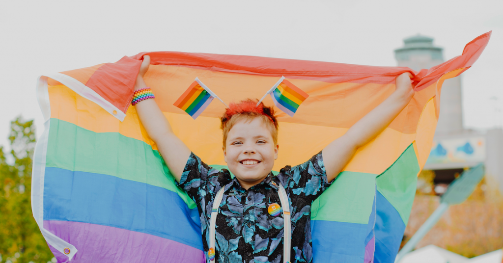 Kid holding pride flag outdoors